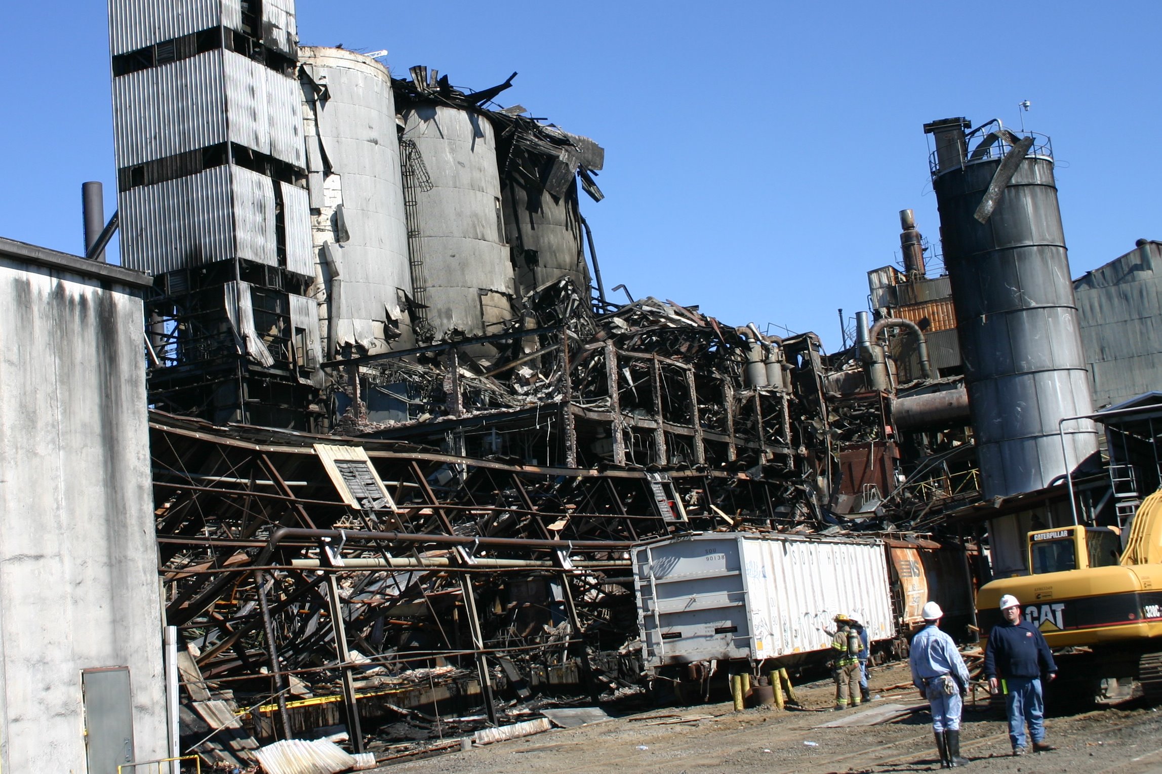 Damaged silos and collapsed packing facilities with personnel in the foreground on 10 February 2008.